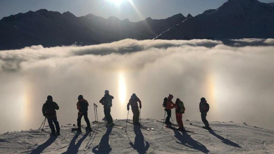 Skigruppe vor Wolken und Sonne