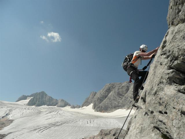 Bergsportler auf einem Klettersteig vor der Gletscherwelt des Hohen Dachsteins