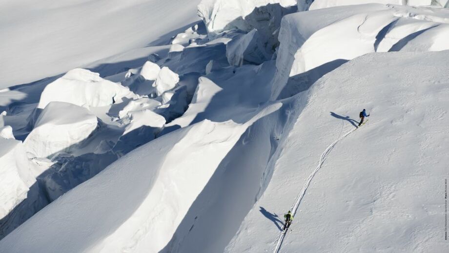 Zwei Skitourengeher im Aufstieg auf Wächte neben Gletscherbruch