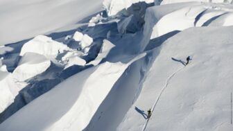 Zwei Skitourengeher im Aufstieg auf Wächte neben Gletscherbruch