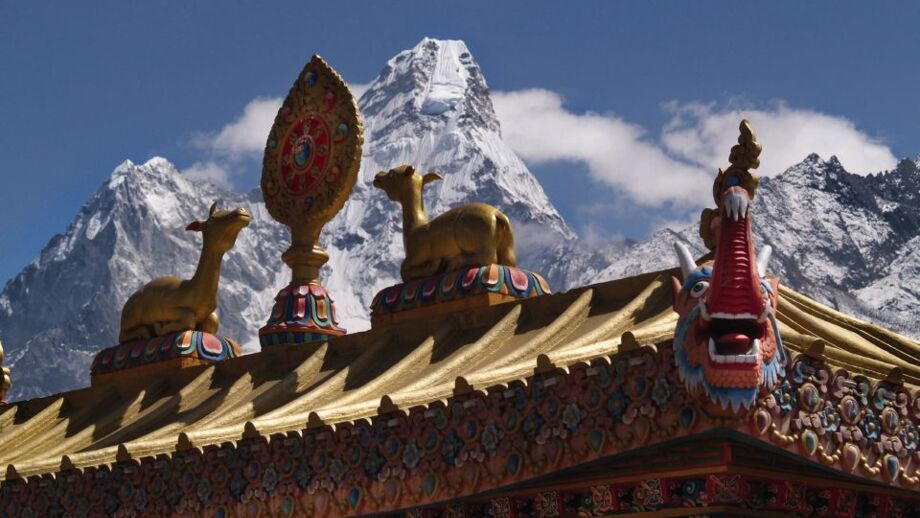 Blick auf den Himalaya im Vordergrund  ein kunstvoll verziertes Dach