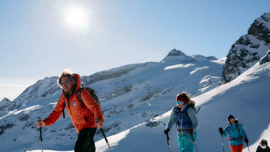Bergführer führt eine Skitourengruppe auf einen Gipfel