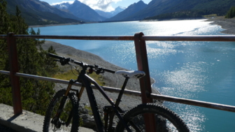 Ein Mountainbike stehend mit Seeblick und der Bergwelt im Hintergrund.
