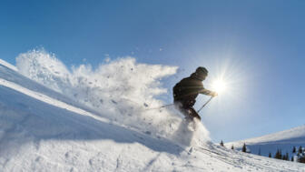 Skifahrer bei der Abfahrt im Tiefschnee