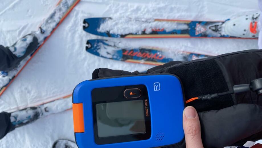 LVS Gerät mit schneebedeckten Ski im Hintergrund