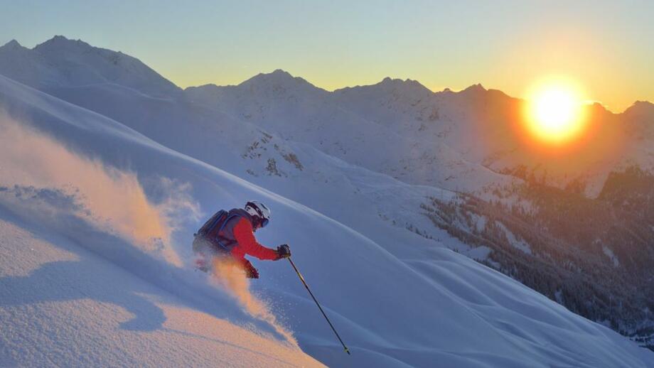 Skifahrer in der Tiefschneeabfahrt bei Sonnenuntergang