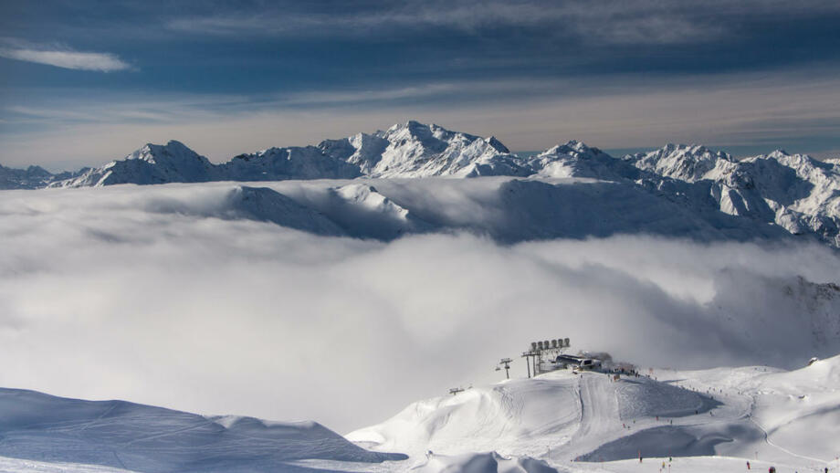 Gondelstation hinter Nebel und vor Gipfelpanorama