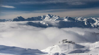 Gondelstation hinter Nebel und vor Gipfelpanorama