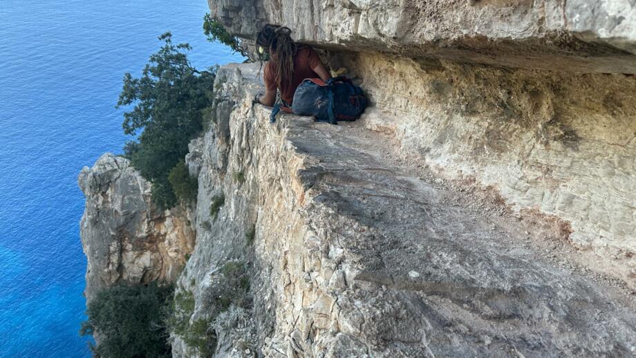 Sehr enger Durchgang an einer sehr steilen Klippe, Wanderer trägt sienen Rücksack und hat einen Helm auf