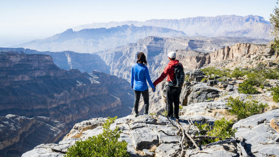 Wander-Pärchen an einem aussichtspunkte mit Blick in einen felsigen Canyon im Oman