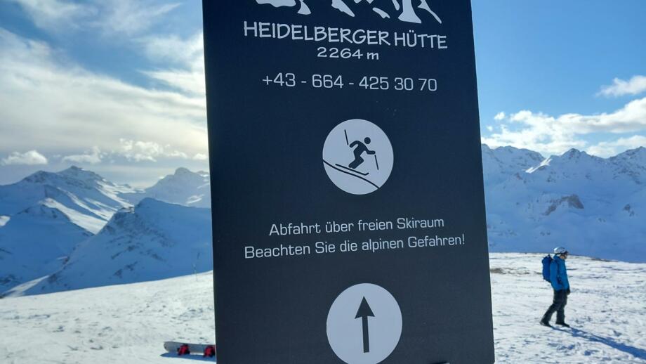 Splitboarder im Hintergrund eines Schildes der Heidelberger Hütte in der Silvretta