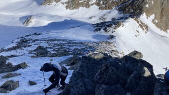 die letzten Meter zum Gipfel steigt eine Skitourengeherin zu Fuß auf