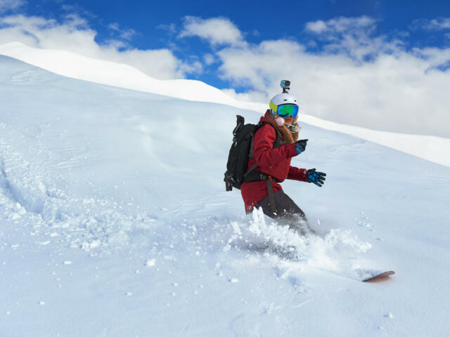 Snowboarderin beim Abfahren mit dem Splitboard bei Tiefschnee