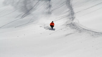 Tiefschneefahrer mit roter Jacke zieht seine Spuren im Powder