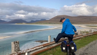 Eine Fahrradfahrerin während der Tour über die äußeren Hebriden in Schottland mit dem Meer im Hintergrund.
