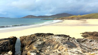 Weitläufiger Ausblick über die Dünenlandschaft und das Meer in Schottland bei Sonnenschein.