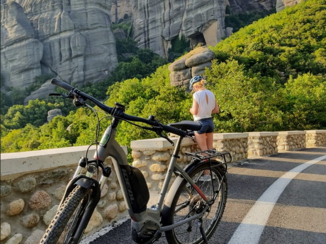 Ein E-MTB auf einer Strasse mit den Metero-Klöstern im Hintergrund