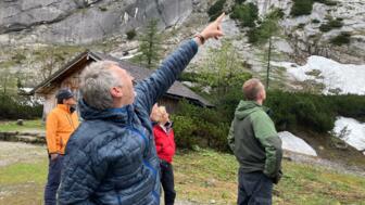 Bergführer zeigt den Teilnehmern eine Stelle am Fels