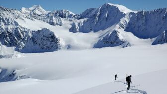 Zwei Skifahrer im unverspurten Tiefschneehang bei Gipfelkuliss