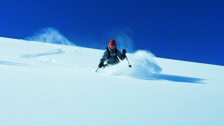 Skifahrer beim Powdern bei blauem Himmel