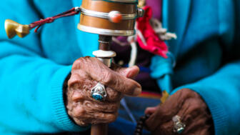 traditionelle buddhistische Gebetsrad in den Händen einer alten Frau