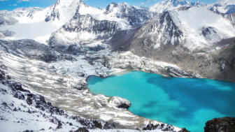 bergseemit dmaragdenem Wasser in verschneiter Hochgebirgslandschaft des Tienshan