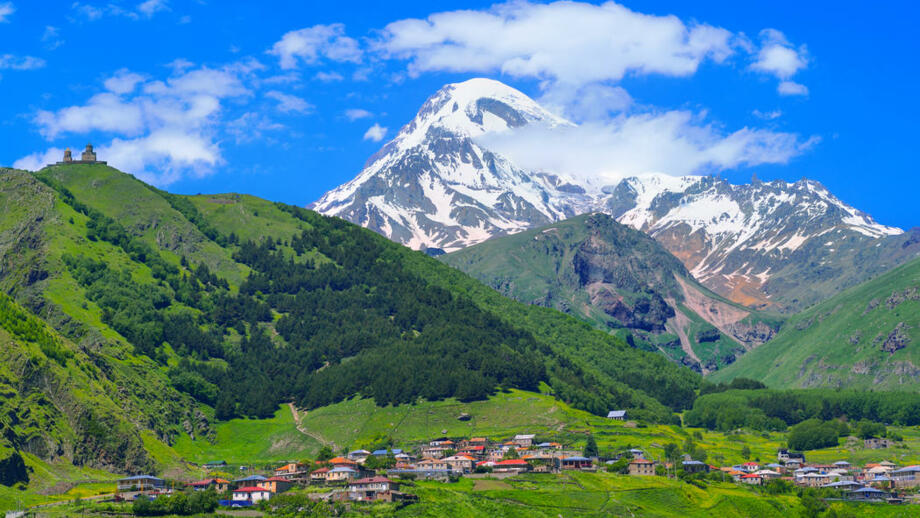 Ort stepantsminda im georgischen kaukasus in grünem Bergland mit dem vergletscherten Fünftausender Kasbek