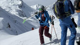Freeriderin mit Ski auf den Schultern