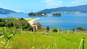 Sandstrand in der Stadt Cesantes und die Insel San Simon, Sommerliche Landschaft der Ria de Vigo