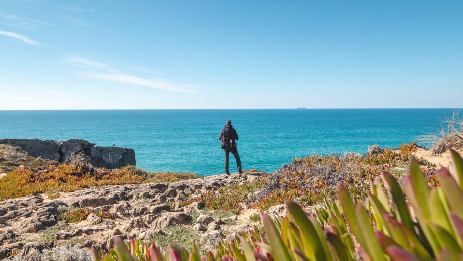 Wanderer mit Blick auf das Meer von Felsklippen bei Vila Nova de Milfontes