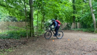 Ein Mountainbiker im Wald während des MTB Fahrtechniktraining bei der Übung Kurven fahren.