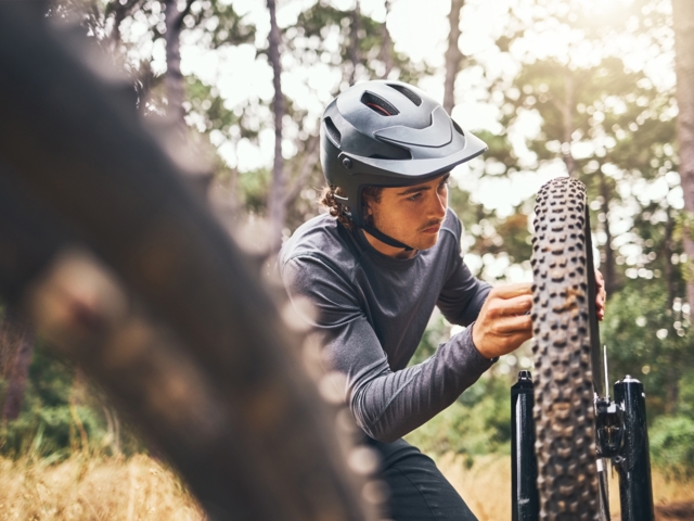 Mountainbiker beim Fahrtechnikkurs - Er überprüft die Sicherheit des Mountainbikes.