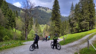 Eine E-MTB Gruppe auf Tour auf einer Forststraße mit einen Berggipfel im Hintergrund.