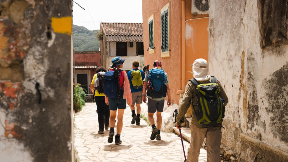 Wanderer in einer Dorfgasse auf Korfu