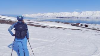 Blick von Hinten auf eine Frau, die einen Fjord in Island bestaunt