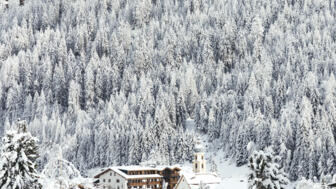 Hotel Kirchenwirt und im Hintergrund schneebedeckte Tannen
