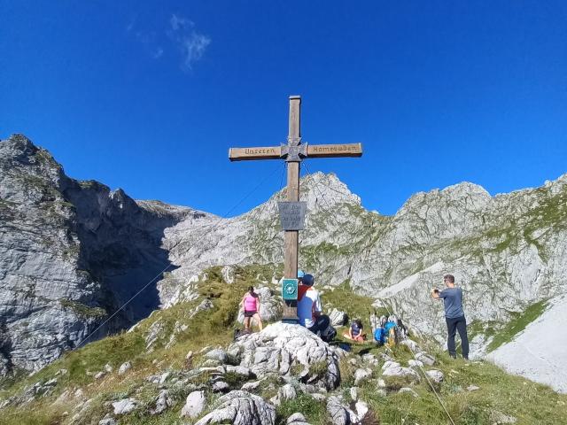 Wanderer an einem Gipfelkreuz in den Berchtesgadener Alpen
