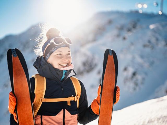 Glückliche Skitourengeherin mit Tourenski im Schnee