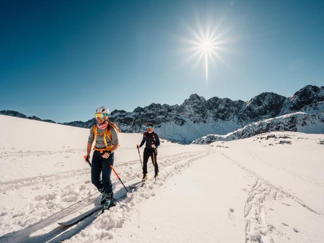 Skitourengeher im Sonnenschein mit Bergpanorama im Hintergrund