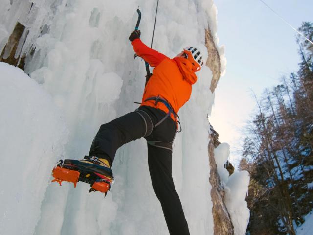 Eiskletterer in der Eiswand bei Sonnenschein