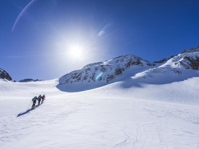 Skitourengruppe in der weißen Winterlandschaft auf dem Weg zum Gipfel