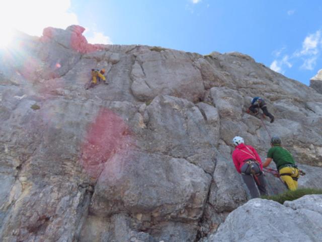 Kletterer erklimmen gesichert eine Felswand