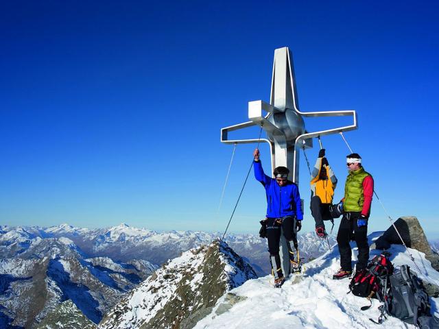 Menschen auf dem Gipfel Zuckerhuetl am Gipfelkreuz