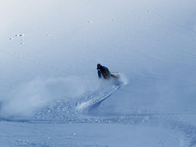 Skifahrer bei der Abfahrt im Tiefschnee