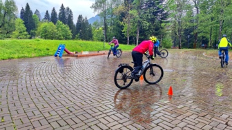 Eine Gruppe an E-Mountainbiker auf einem gepflasterten Platz bei leichten Regen während einer E-MTB Fahrtechnik-Trainingsübung.