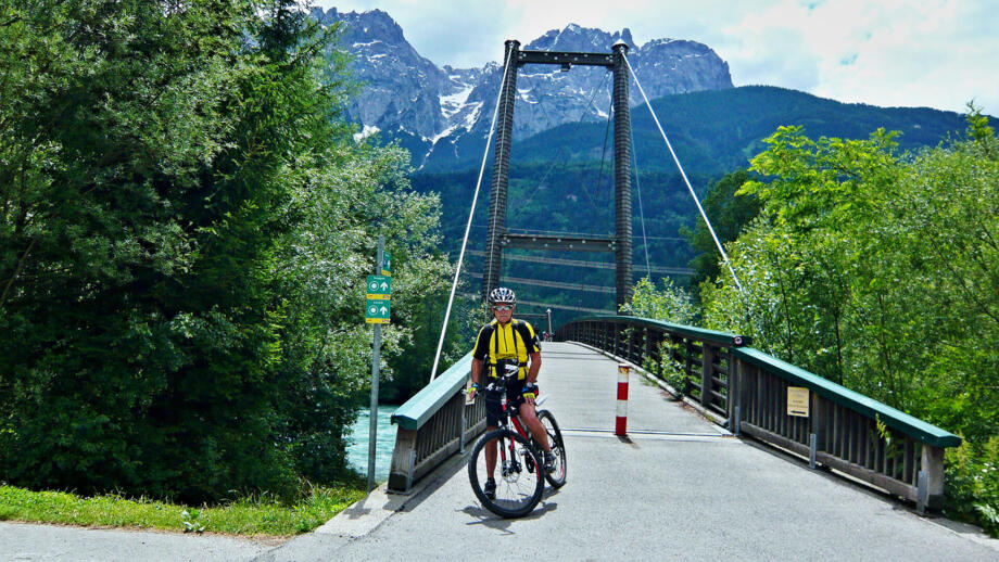 Ein Crossbiker steht auf einer Strasse nachdem er eine Brücke überquert hat.