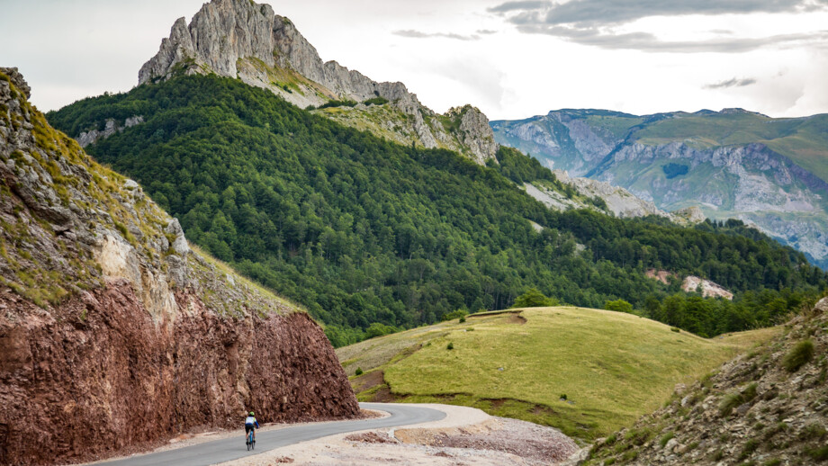 Ein Mountainbiker unterwegs durch die dinarischen Alpen. Im Hintergrund sind die Berge zu sehen.