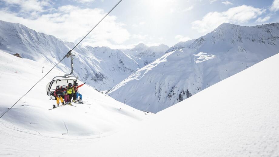 Vier Skifahrer und Snowboarder im Sessellift