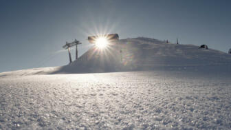 Die Sonne blitzt durch die Gondel Station auf den weißen Schnee