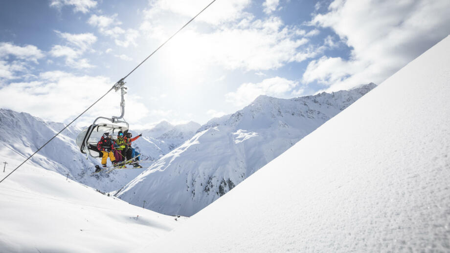 Skifahrer im Sessellift mit Schnee im Vordergrund